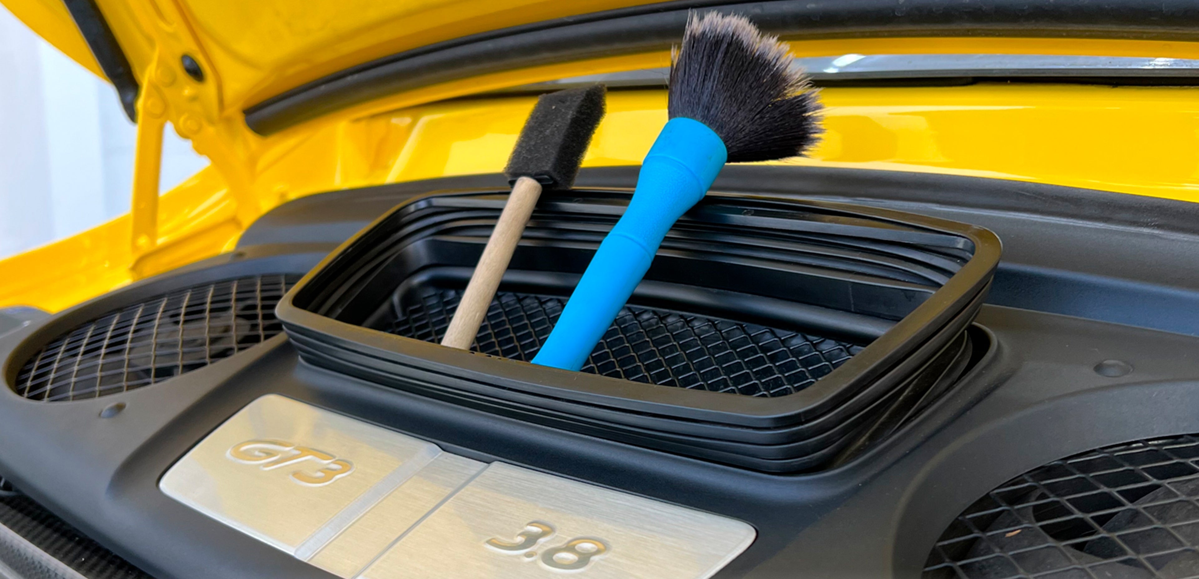 Kit d'accessoires de detailing automobile professionnel posé près d'une carrosserie pour illustrer l'importance d'un bon équipement