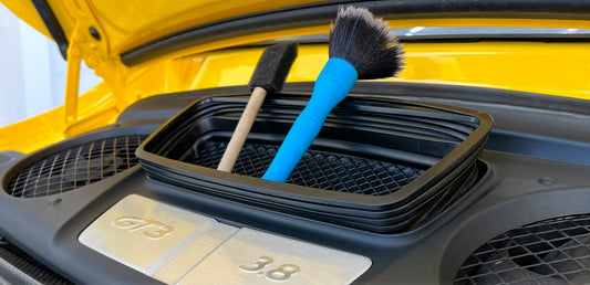 Kit d'accessoires de detailing automobile professionnel posé près d'une carrosserie pour illustrer l'importance d'un bon équipement